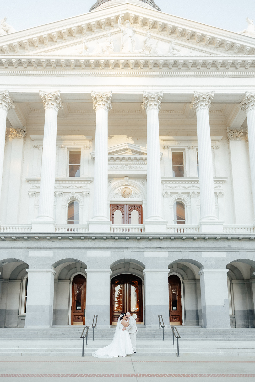 A bride and groom in front of the Sacramento State Capitol